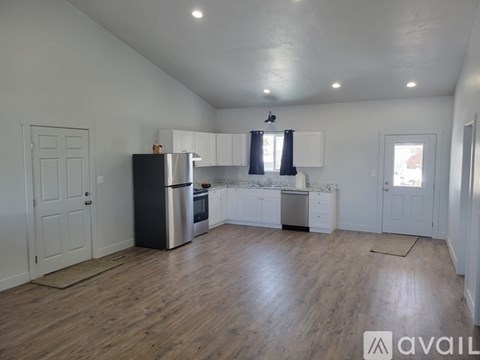 A kitchen with white cabinets and a black fridge is available for rent.