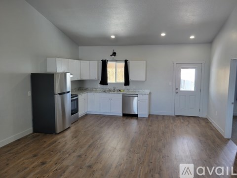 A kitchen with white cabinets and a black refrigerator.