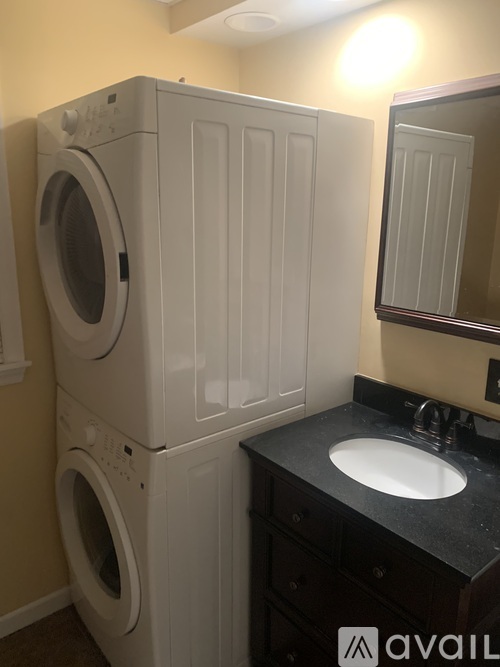 A stack of two white washing machines in a laundry room.
