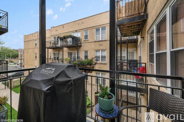 A balcony with a grill and a table with a potted plant.