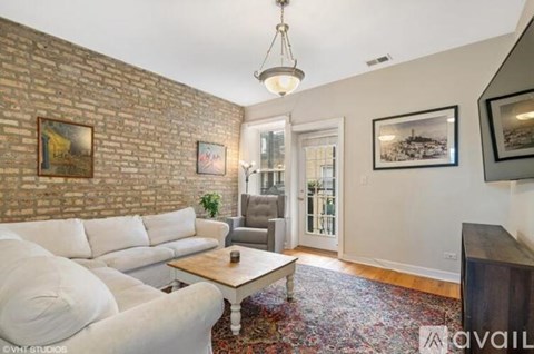 A living room with a white couch and a brick wall.