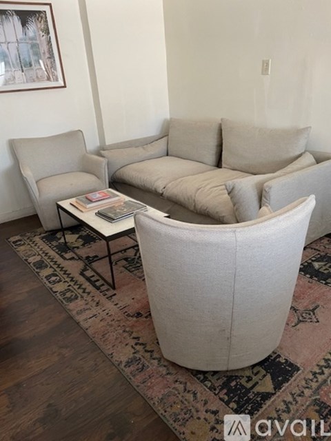 A living room with a grey sofa, a grey armchair, and a coffee table with magazines on it.
