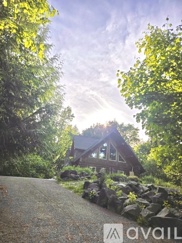 A house is surrounded by trees and rocks in the foreground.