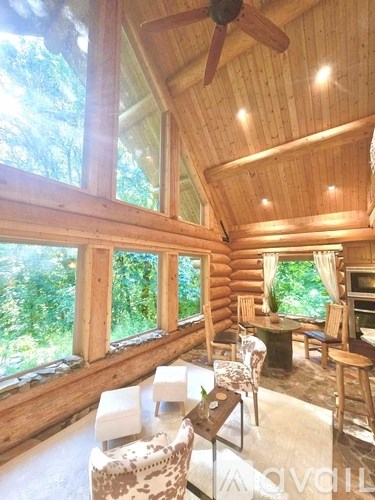 A living room with a ceiling fan and a table with chairs.