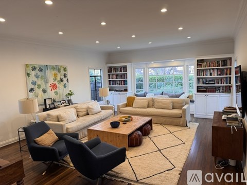 A living room with a large painting on the wall and a bookshelf filled with books.