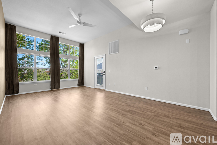 A spacious room with a ceiling fan and a large window with curtains.