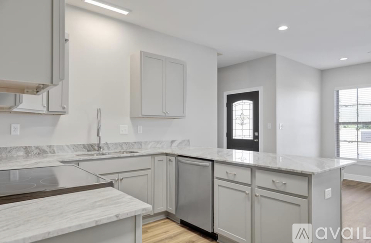 A modern kitchen with a marble countertop and stainless steel appliances.