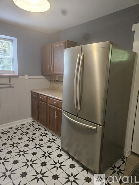 A kitchen with a stainless steel refrigerator and wooden cabinets.