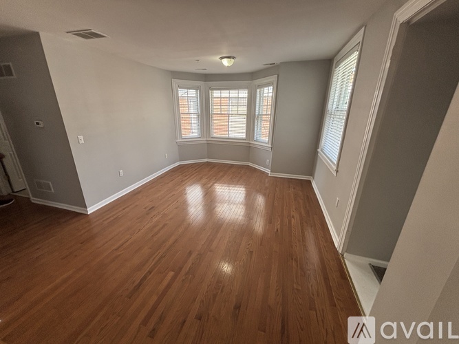 A spacious room with wooden flooring and a large window.