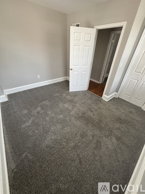A room with a carpeted floor and a white door.