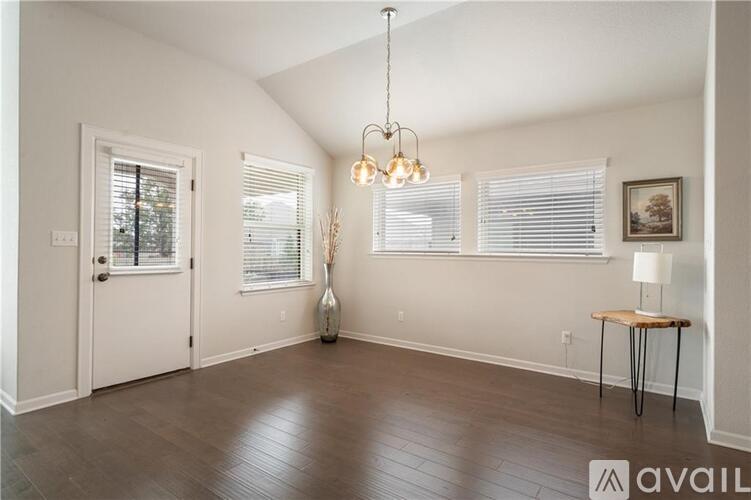 A room with a white door, a table with a lamp, and a vase on the floor.