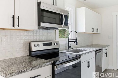 A kitchen with white cabinets and a granite countertop.