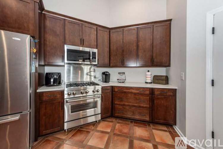 A kitchen with brown cabinets and a stainless steel refrigerator.
