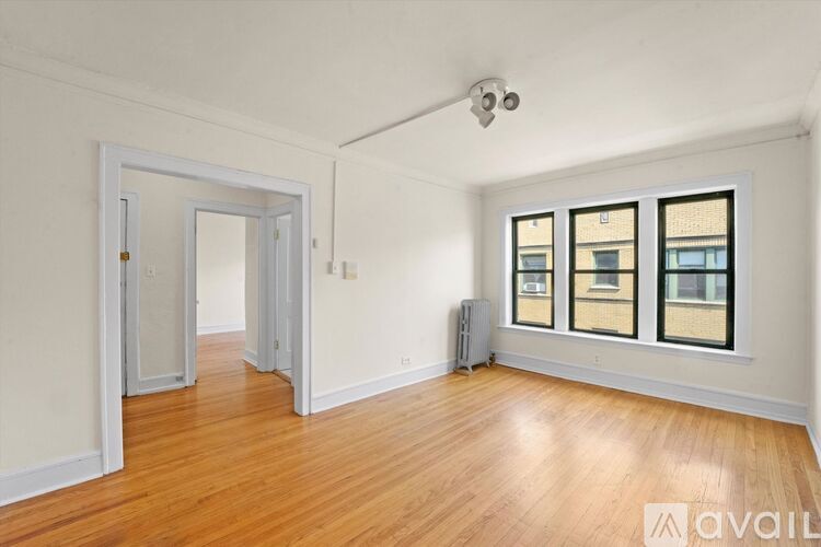 A room with wooden floors and a window with a view of a building.