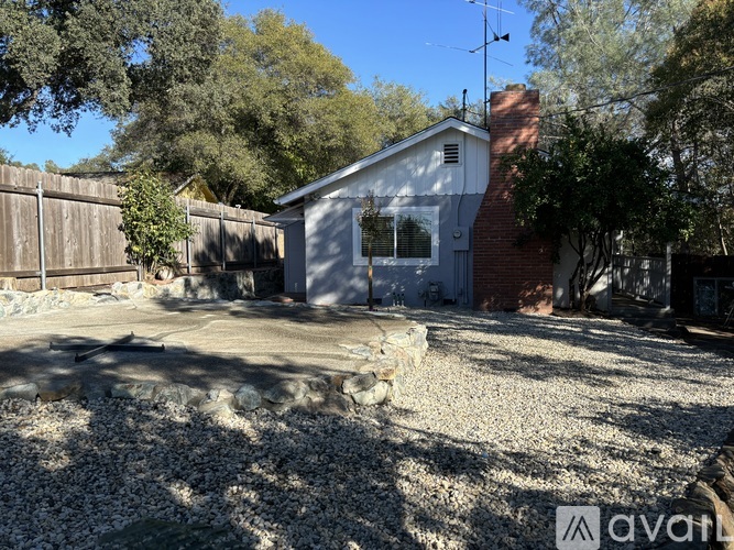 A house with a gravel driveway and a fence in the background.