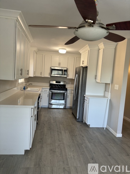 A kitchen with white cabinets and a fan.