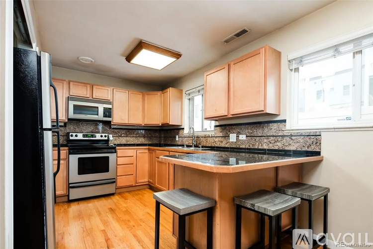 A kitchen with wooden cabinets and a black refrigerator.