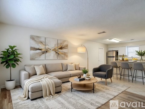 A living room with a grey couch, a coffee table, and a large abstract painting on the wall.