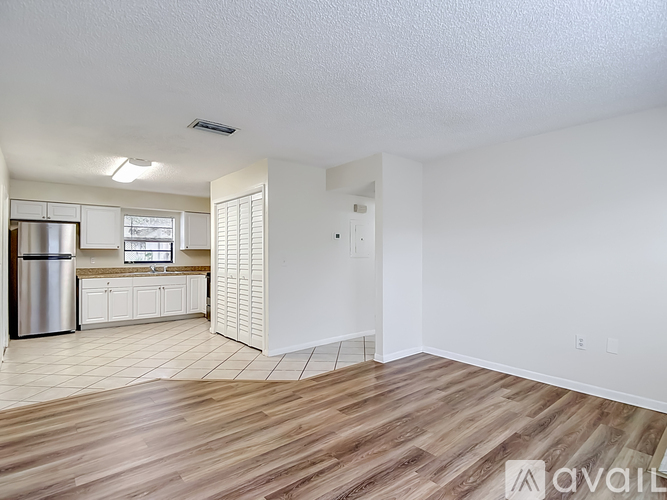 A spacious kitchen with white cabinets and a wooden floor.
