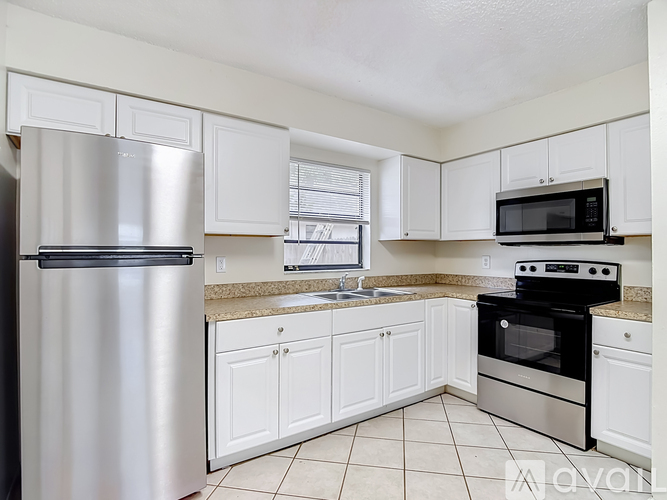 A kitchen with white cabinets and a stainless steel refrigerator.
