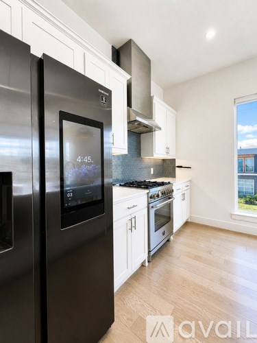 A modern kitchen with a stainless steel refrigerator and a digital display showing the time.