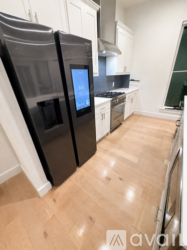 A kitchen with a black fridge and wooden flooring.