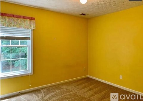 A room with yellow walls and a window with a view of trees.