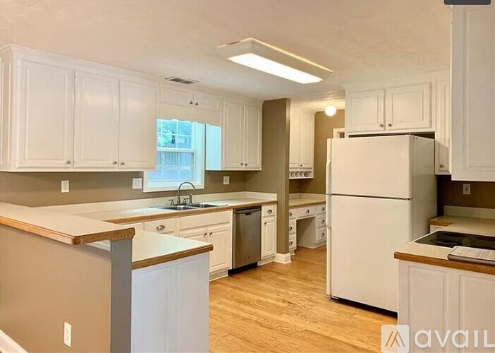 A kitchen with white cabinets and a white refrigerator.