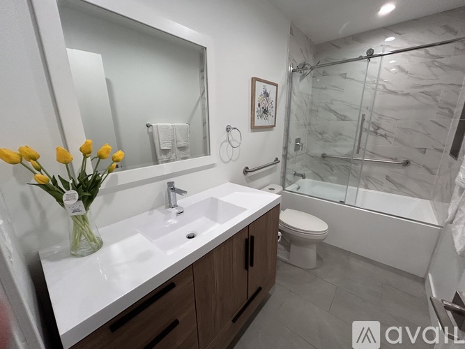 A bathroom with a white sink, a mirror, a toilet, and a shower.