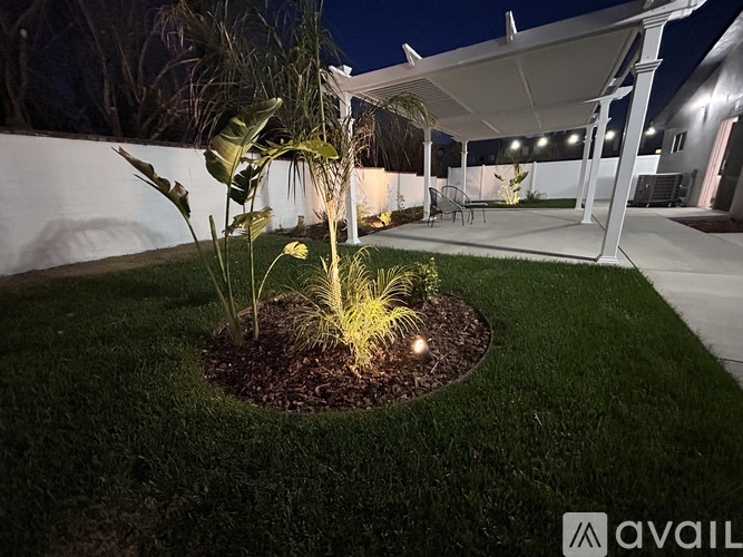 A garden with a white pergola and a lawn.