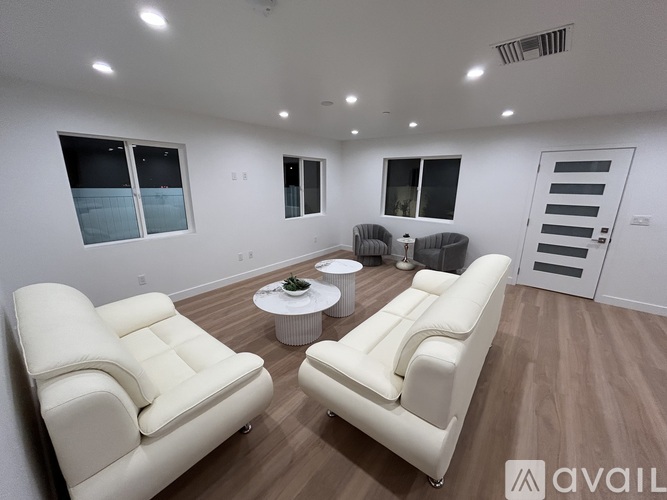 A living room with white leather furniture and a round coffee table.