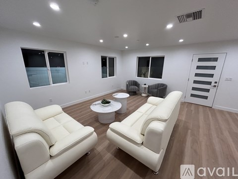 A living room with white leather furniture and a round coffee table.