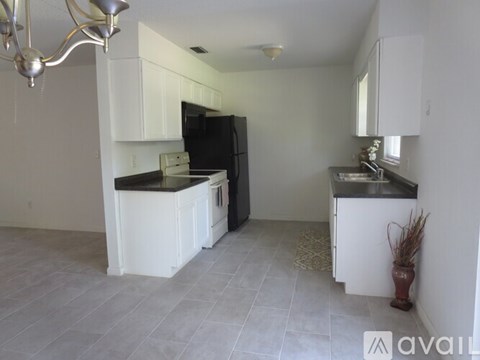 A kitchen with white cabinets and a black refrigerator.