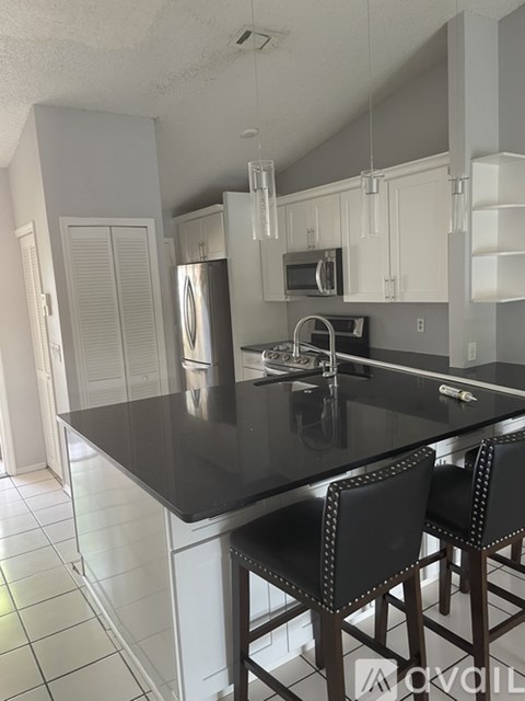 A kitchen with a black counter top and white cabinets.