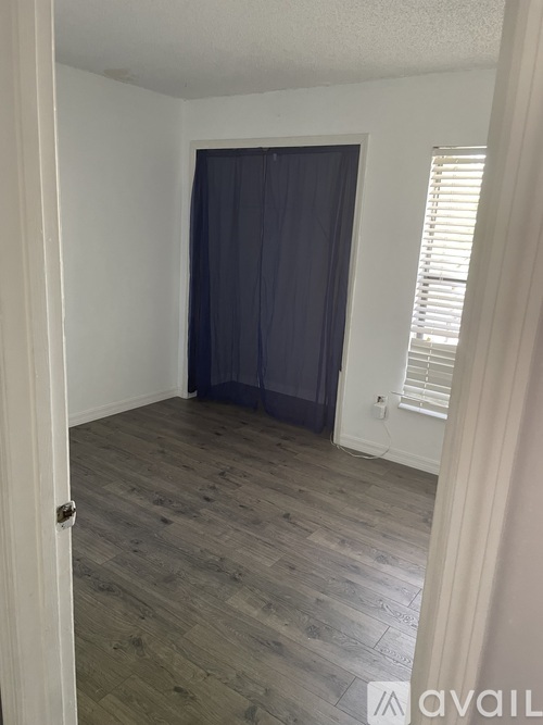A room with a grey curtain and wooden floor.