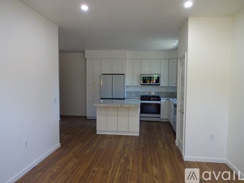 A kitchen with white cabinets and a wooden floor.