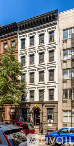 A row of buildings with cars parked in front.