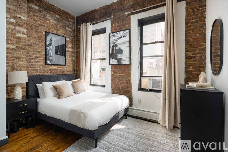 A bedroom with a brick wall and a bed with a white comforter.