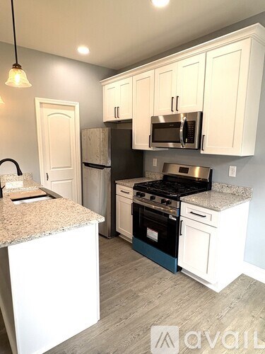 A kitchen with white cabinets and a granite countertop.