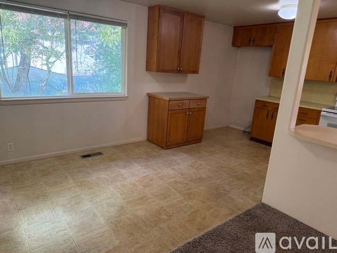 A room with a window, wooden cabinets, and a tiled floor.