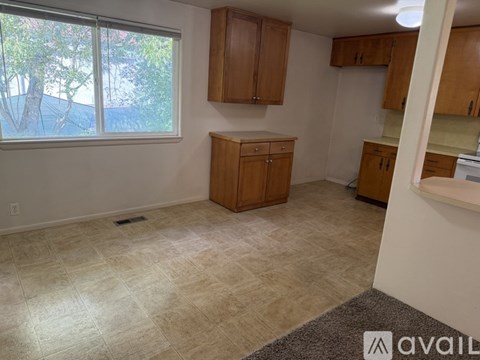 A room with a window, wooden cabinets, and a tiled floor.
