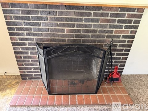 A black fireplace screen is on a brick fireplace.