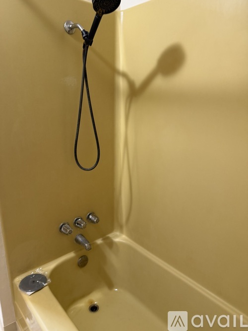 A yellow bathtub with a shower head and faucet.