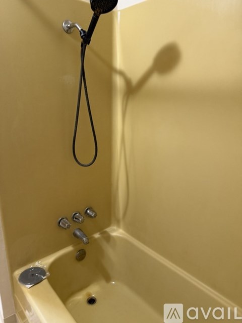 A yellow bathtub with a shower head and faucet.