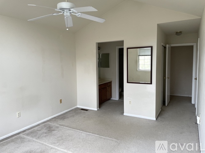 A room with a ceiling fan and carpeted floor.