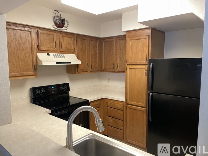 A kitchen with wooden cabinets and a black refrigerator.