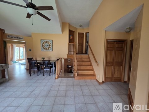 A living room with a dining table and chairs, a staircase, and a ceiling fan.