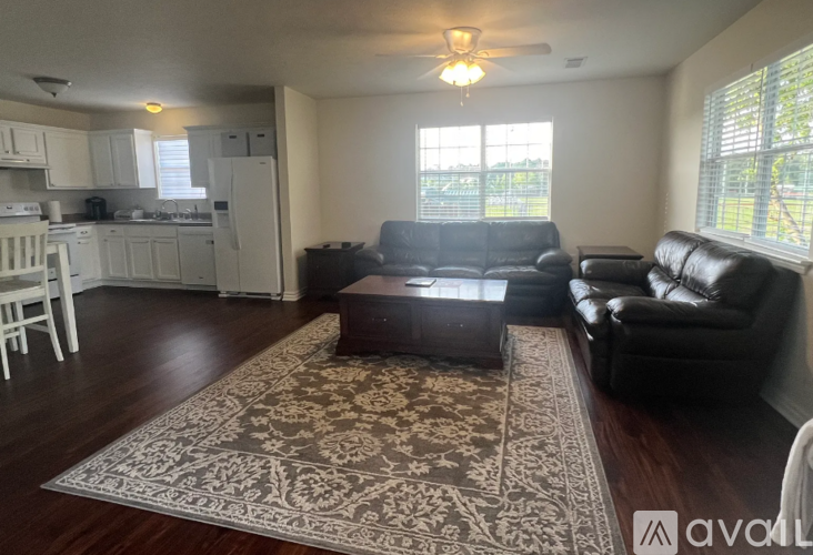 A living room with a rug and two leather couches.