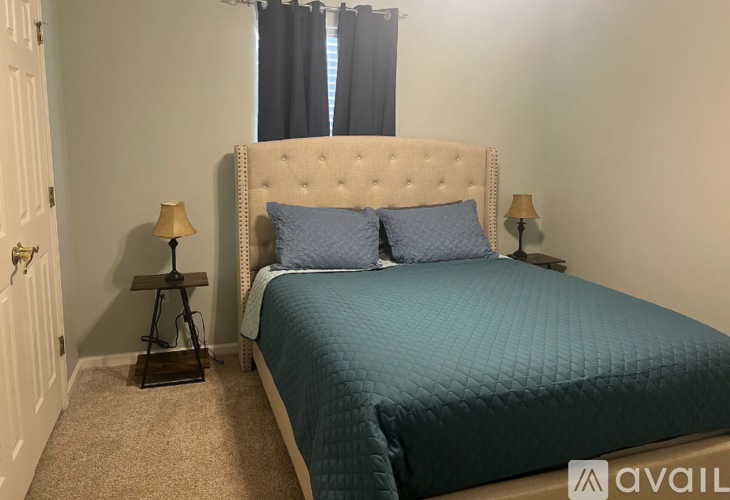 A bedroom with a bed, two lamps, and a window.
