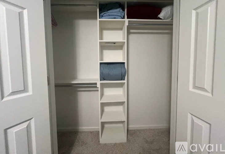 A white closet with shelves and drawers is open.